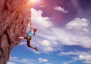 Woman rock climbing on side of steep cliff