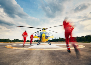 Search and Rescue team members racing towards a yellow helicopter on a helipad