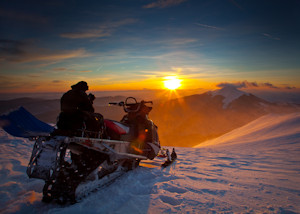 Snowmobiler overlooking mountains at sunrise