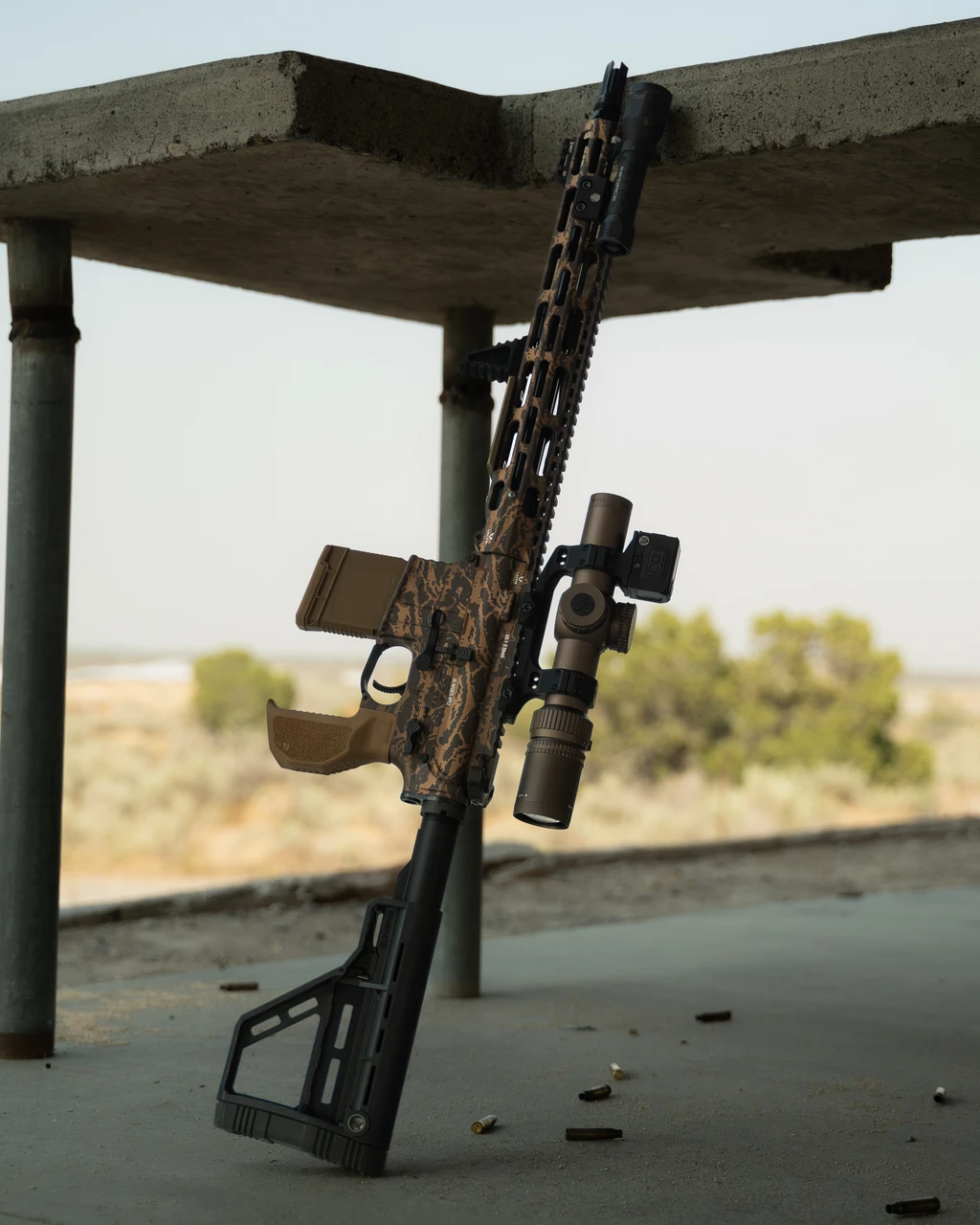 SPR 06 full build leaning under a concrete shelter in the desert with spent brass on the ground