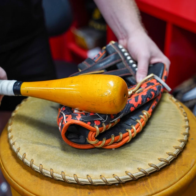 A glove being worked with a glove mallet on a shaping stand