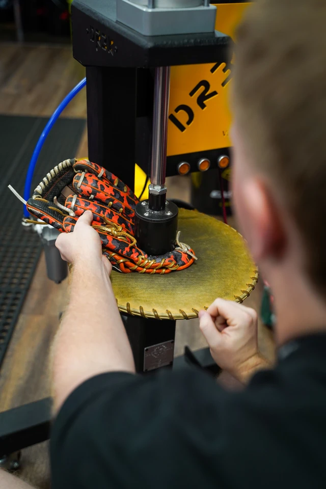 A baseball glove being shaped under the hydraulic press