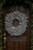 White pine cone wreath on a arched wooden door.