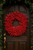 Red pine cone wreath on wood door.