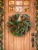 Beautiful handmade magnolia wreath hangning on a wooden door.