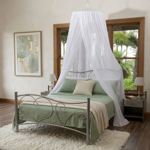 Round cotton mosquito net hanging from one ceiling point over a double bed