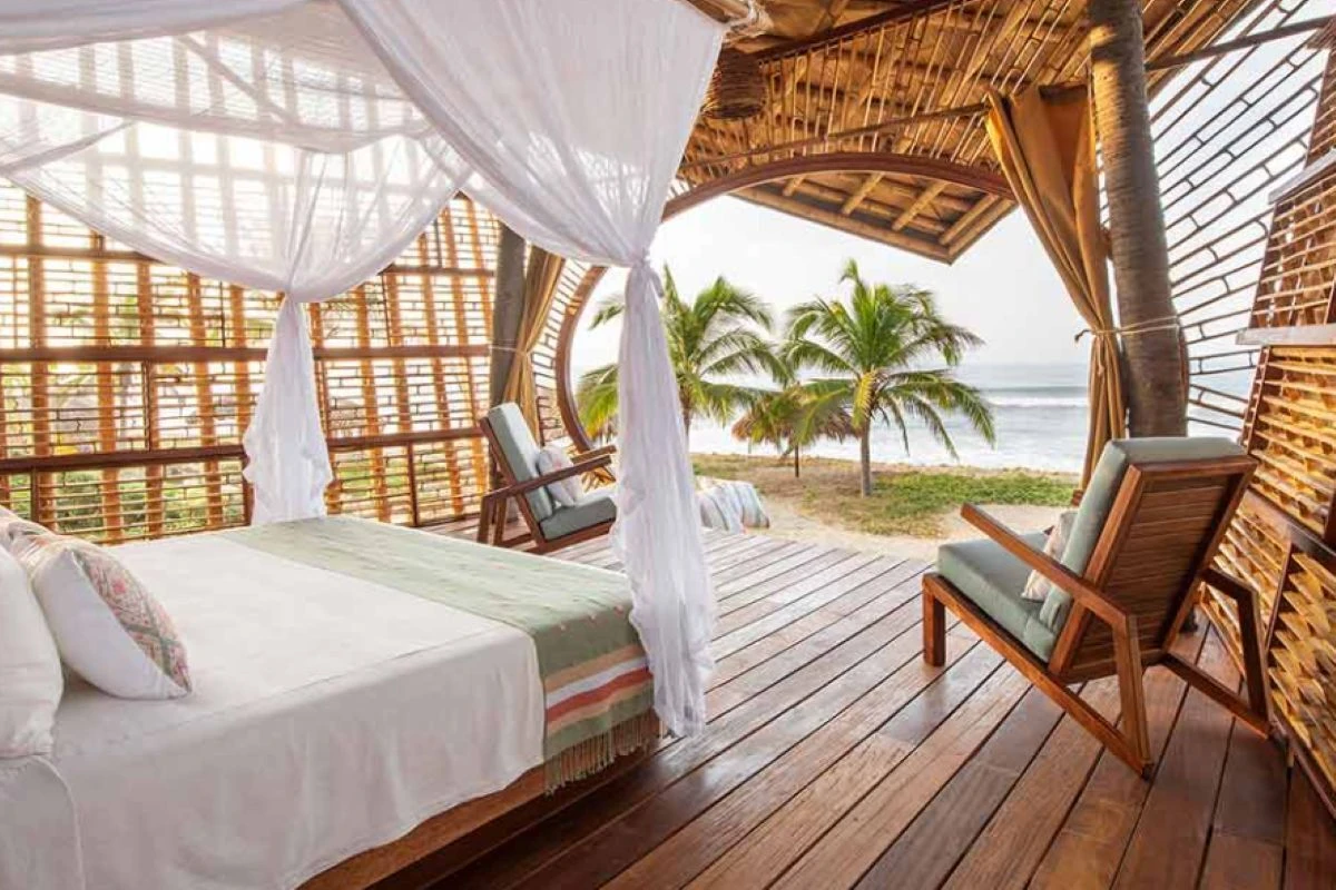 White cotton box mosquito net bed canopy over an open-air resort bed at Playa Viva, Mexico