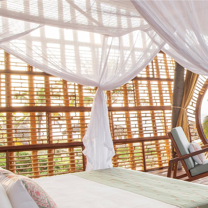 White cotton mosquito net bed canopy over a resort bed at Playa Viva, Mexico