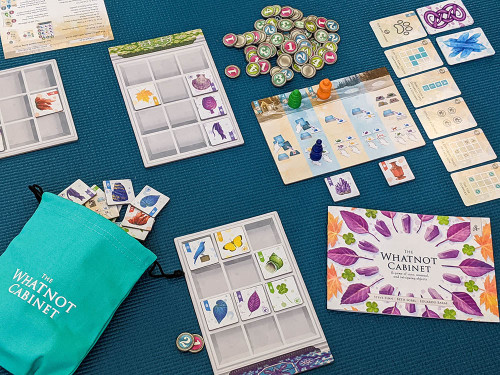 The Whatnot Cabinet gameplay, including  a bag of object tiles and tiles arranged on curio boards