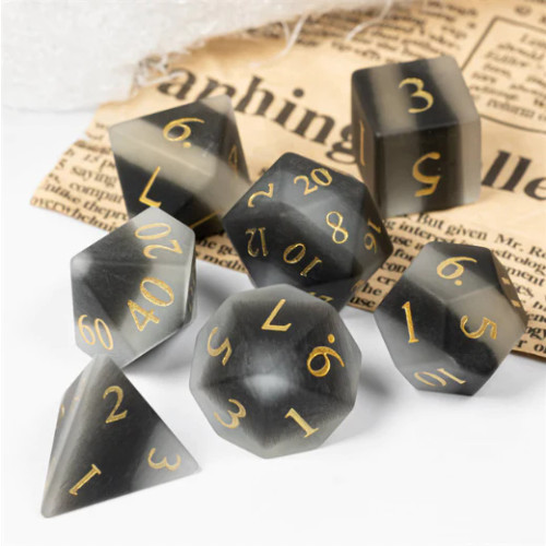 Set of seven Frosted Black & White Cat's Eyed gemstone dice, on an old newspaper