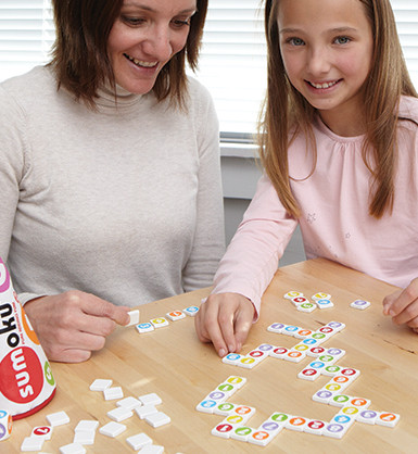 Adult woman and school-aged girl playing Sumoku on a table
