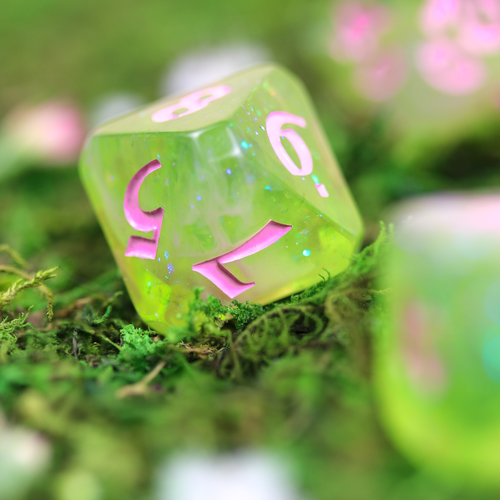 Close up of a Translucent green with silver-blue sparkles and pink inking dice