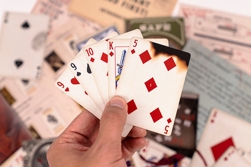A hand of cards, the 5 of Diamonds partly burned
