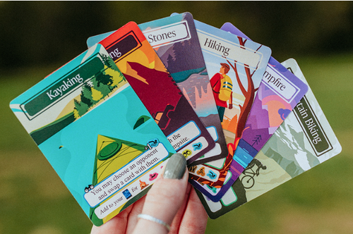 A hand holds example cards from the game