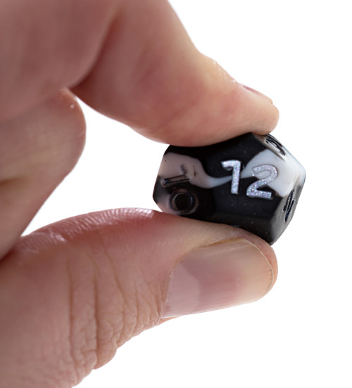 A 20-sided die being squished between two fingers
