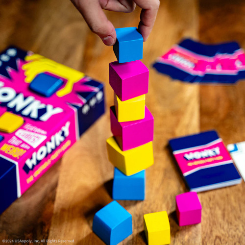 A hand adds a cube to the top of a tower of other cubes