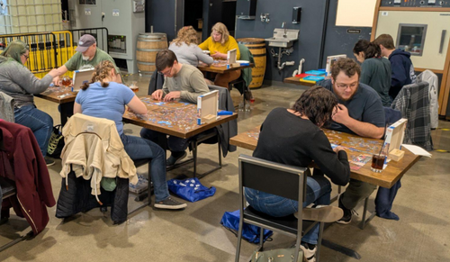 People sit at tables working on jigsaw puzzles
