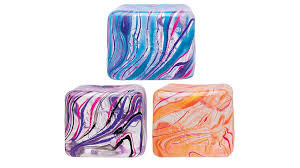 An assortment of different colors of Niceberg-sized NeeDoh sensory squish cubes with unique swirls.  There is a blue-purple-pink swirl cube, a pink-purple-black swirl cube, and a red-orange swirl cube.