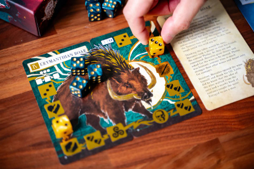 A hand places dice on the Erymanthian Boar labor cards
