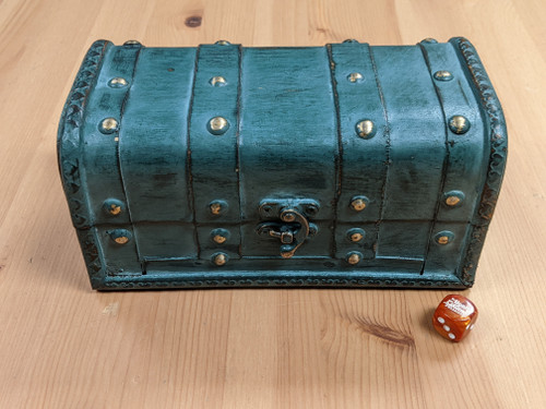 A aqua hued Large Dice Chest- closed, with a D6 next to it for scale, dice not included