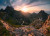 the sun peaking over a mountain with a snake like path the sun peaking over a mountain with a snake like path