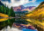 a valley with water reflecting the mountains and gold and green forestry