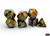 Set of seven black RPG dice with green and orange paint patterns and gold numerals