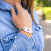 A close-up of a person wearing a silver-toned medical alert bracelet on their left wrist. The bracelet features a white rectangular plate with intricate silver patterns and a red Star of Life symbol in the center. The person is dressed in a light blue denim shirt with visible stitching and a metal snap button. Their hand is slightly raised near their shoulder in a casual pose. The background is blurred, showing green and yellow tones, suggesting an outdoor setting with foliage and sunlight. The image highlights the bracelet as both a stylish accessory and a vital medical device. A close-up of a person wearing a silver-toned medical alert bracelet on their left wrist. The bracelet features a white rectangular plate with intricate silver patterns and a red Star of Life symbol in the center. The person is dressed in a light blue denim shirt with visible stitching and a metal snap button. Their hand is slightly raised near their shoulder in a casual pose. The background is blurred, showing green and yellow tones, suggesting an outdoor setting with foliage and sunlight. The image highlights the bracelet as both a stylish accessory and a vital medical device.