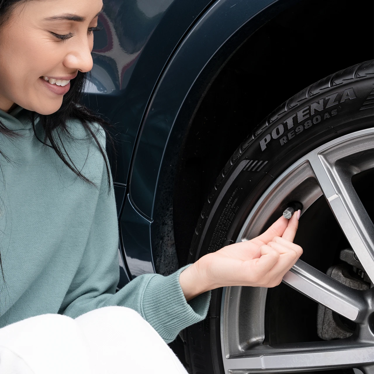 Woman installing a STEEL HAWK stainless steel valve cap on a car tire