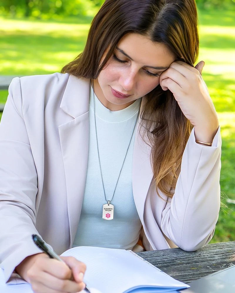 Woman working at a desk wearing a medical ID necklace