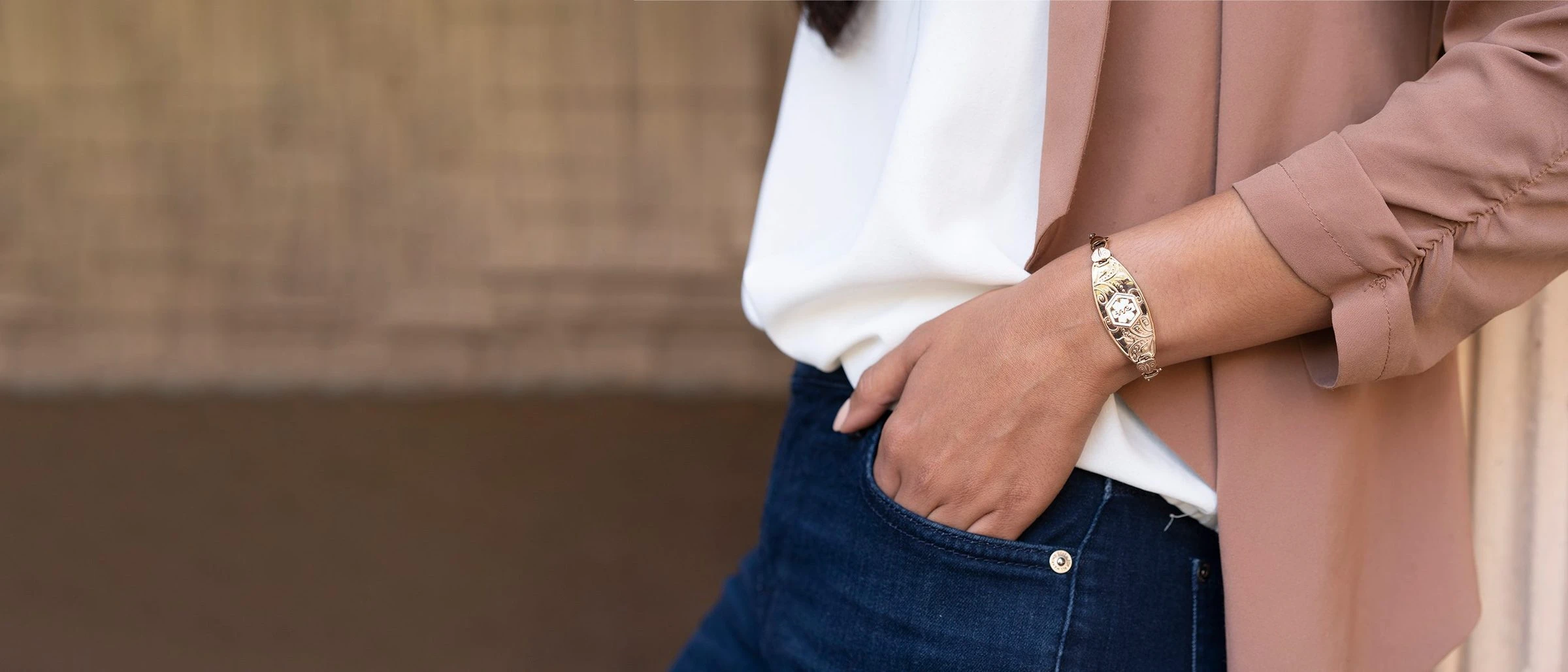 Woman wearing a rose gold Divoti medical ID bracelet, hand in her jeans pocket