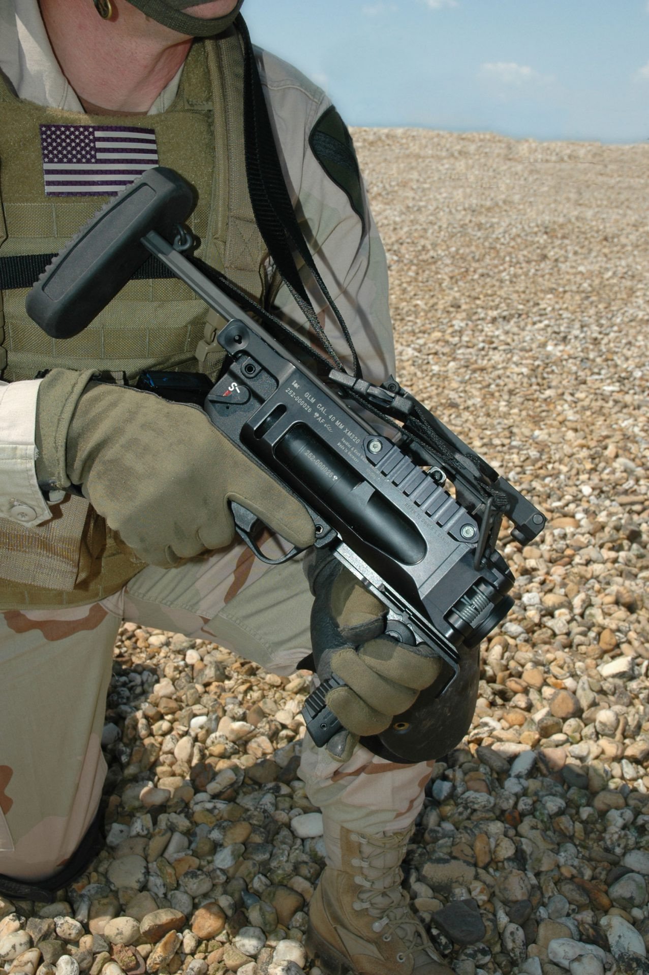 The HK GLM (Grenade Launcher Module) is a 40x46mm system that can be used with either lethal or less-lethal munitions for Military or Law Enforcement use.
The HK GLM is a light weight stand-alone or host weapon mounted 40x46mm single shot grenade launcher that is side breach opening/ loading, utilizing a double-action trigger with ambidextrous safety and controls. The system incorporates a collapsing/extendable and removable stock as well as other accessories.
It is capable of fifiring multiple use munitions/projectiles to include High Explosive “HE” rounds to an effective range of 350M, illumination rounds for signaling and visibility, Smoke for screening and obscuring, CS, and various less lethal munitions for crowd and riot control at closer ranges.
The GLM can be used in a Stand-Alone Mode (SAM) or it can be host mounted to another riflfle system via optional mounting solutions. The common mounting solutions are for the HK416, HK417, M16A2,
and M4.
Background:
In the 1970s Heckler & Koch “HK” developed and produced the 40x46mm Steel stand-alone HK69 grenade launcher which was similar in performance to the US Military M79 grenade launcher at the time.
HK made updates to our existing grenade launchers through internal product improvement efforts which became the HK Grenade Launcher Module (GLM) 40x46mm based on our previous HK 40x46mm systems. The HK GLM was offered to the US Army in 2005 and tested with limited production in 2006 as the XM320. After successful testing the system was approved and type-classifified and procured as the M320/M320A1 (for use on the M16A2 or M4 as well as a stand-alone system) by the US Army in 2008. HK has provided over 40,000 HK GLM type systems to the USA for Military or Law Enforcement use.
HK weapon systems are manufactured with an ISO-9001 quality and test process. HK weapons are additionally tested to the NATO AC/225 requirements.