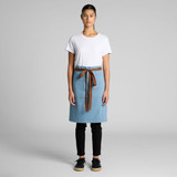 A denim half apron in light blue with a brown tie, worn over a white t-shirt and black pants. Features a logo.