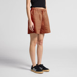Linen shorts in a rust orange colour, featuring an elastic waistband and drawstring, styled with black sneakers.
