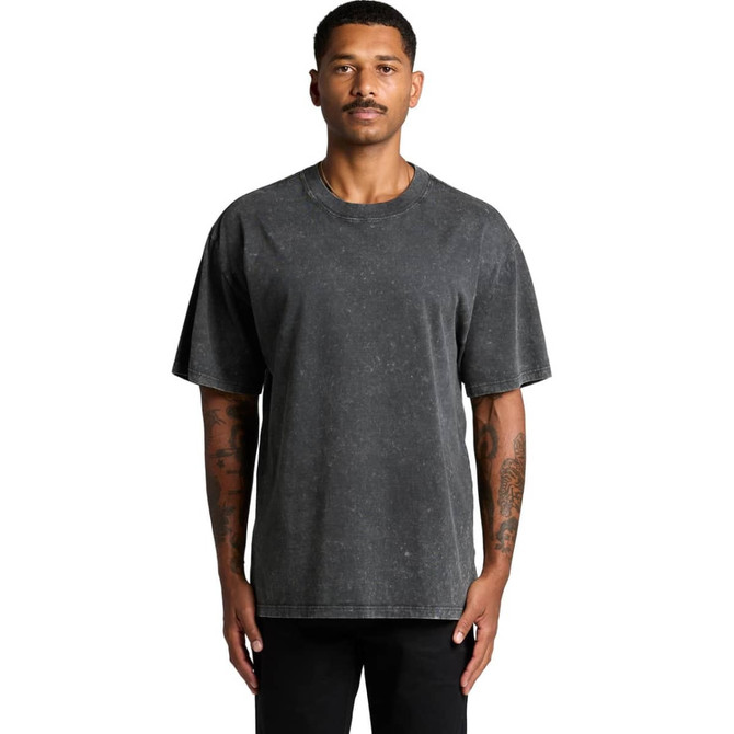 A man wearing a stone wash heavy tee in a dark grey shade. The shirt features a logo on it.