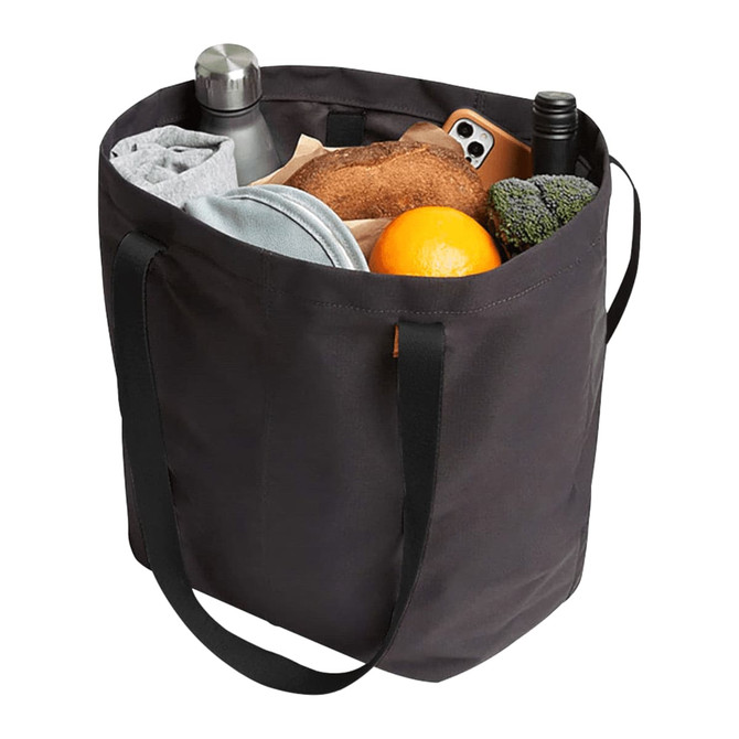 A black tote bag filled with a drink bottle, orange, bread, towel, and broccoli. It has two handles and a logo.