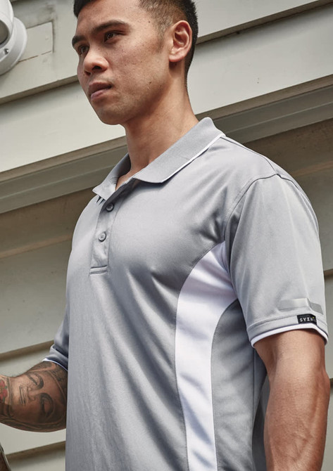 A grey short sleeve polo featuring white accents and a logo on the sleeve. The model is standing outdoors.