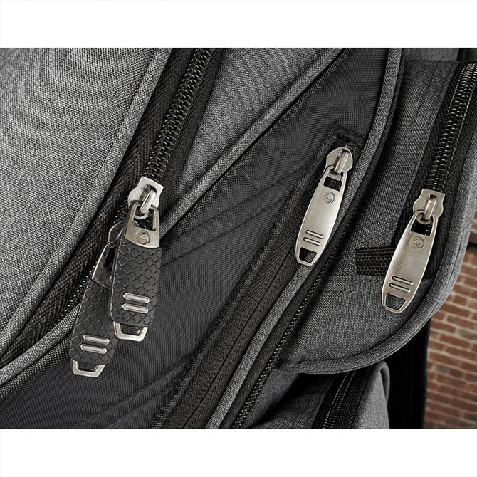 A close-up of a grey backpack featuring multiple zippers and a textured zipper pull. It has a logo on one of the zippers.