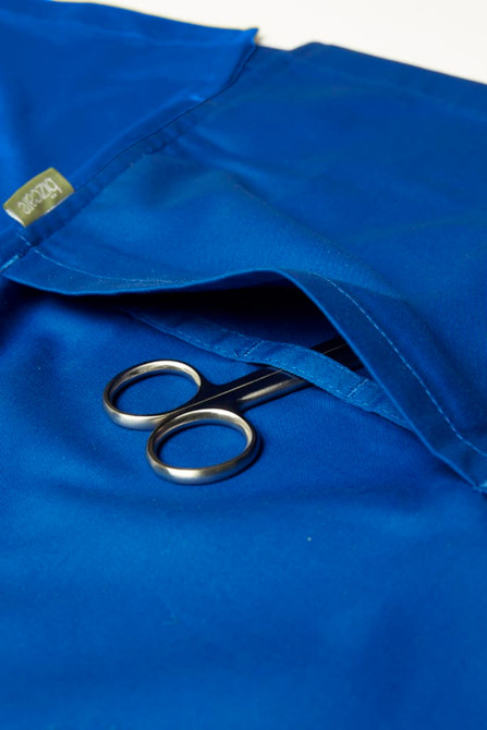 A blue women's scrub top with a pocket containing a pair of scissors and featuring a logo.