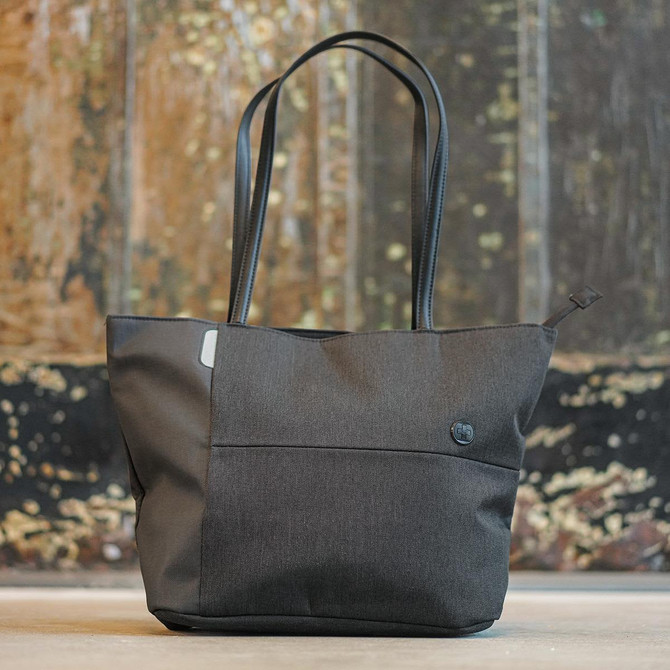 A dark grey tote bag with black handles and a subtle logo on the side, featuring a zip closure.