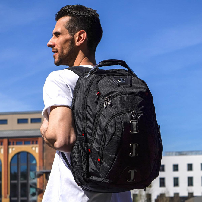 A man wearing a white shirt carries a black Swissdigital Pixel Backpack on his back against a clear blue sky.