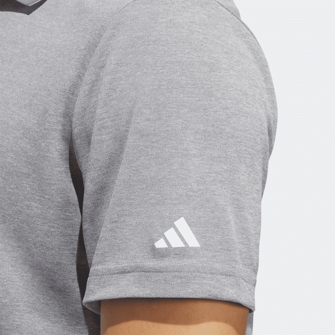 A grey polo shirt with a short sleeve featuring a logo on the arm.
