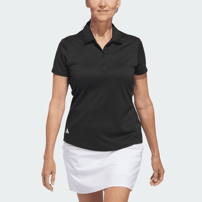 A black polo shirt with a collar and short sleeves, featuring a logo. Worn by a model with a white skirt.