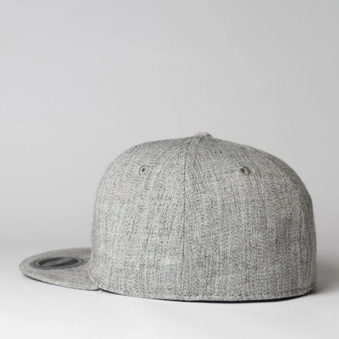 A grey fitted cap with a flat peak and six panels, featuring a logo on the side.
