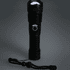 A black LED flashlight with a textured grip and a lanyard, featuring a circular button on its body.