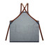 A denim apron in blue with brown straps, featuring a pocket at the front and a logo.