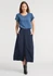 A women's short sleeve blouse in blue, paired with a long navy skirt. The model has a logo on the blouse.