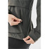 A hand adjusting a zippered pocket on a women's dark green rain jacket, featuring a logo on the fabric.
