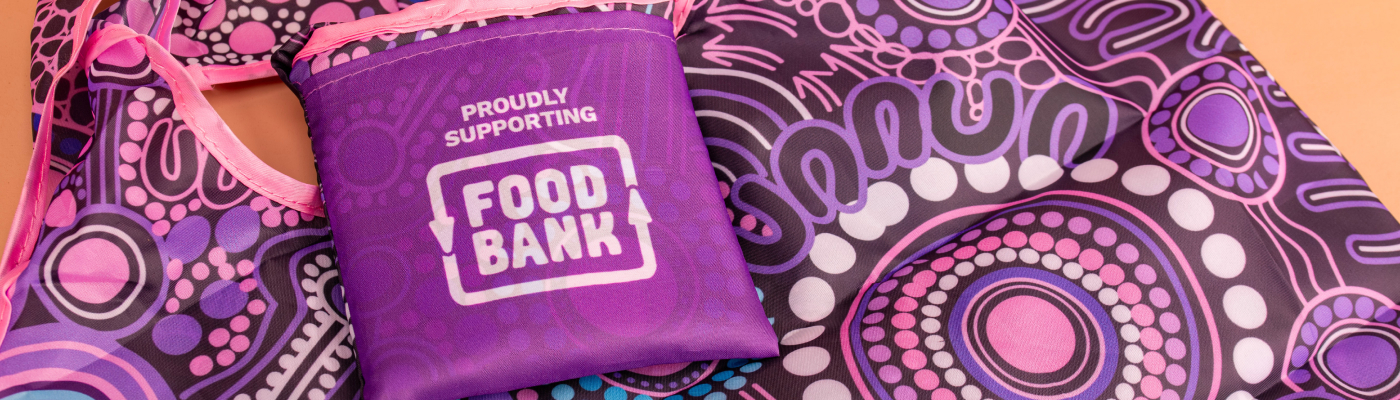 Purple and pink reusable bag with Aboriginal-inspired design, featuring a compact pouch labeled Proudly Supporting Food Bank