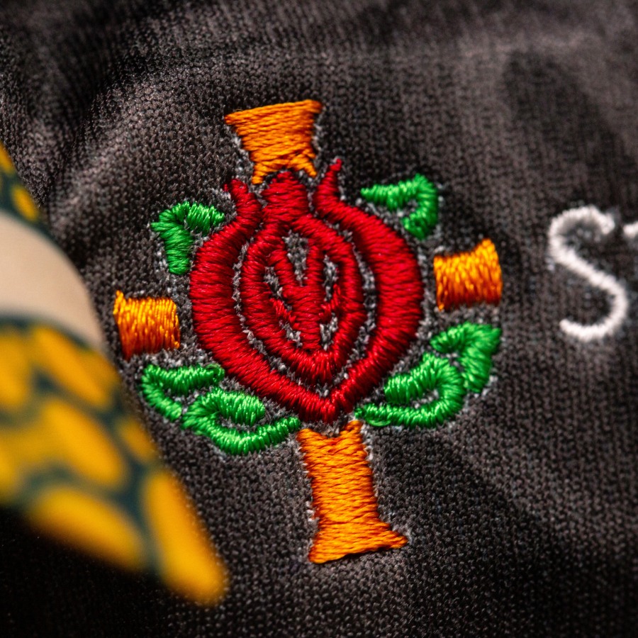 A colorful embroidered logo on the chest, featuring an abstract landscape design.